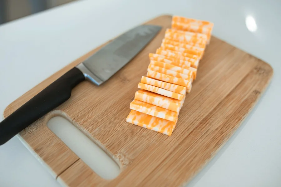 Creamy Havarti Cheese Slices Thick creamy Havarti cheese slices on a rustic wooden cutting board with fresh herbs