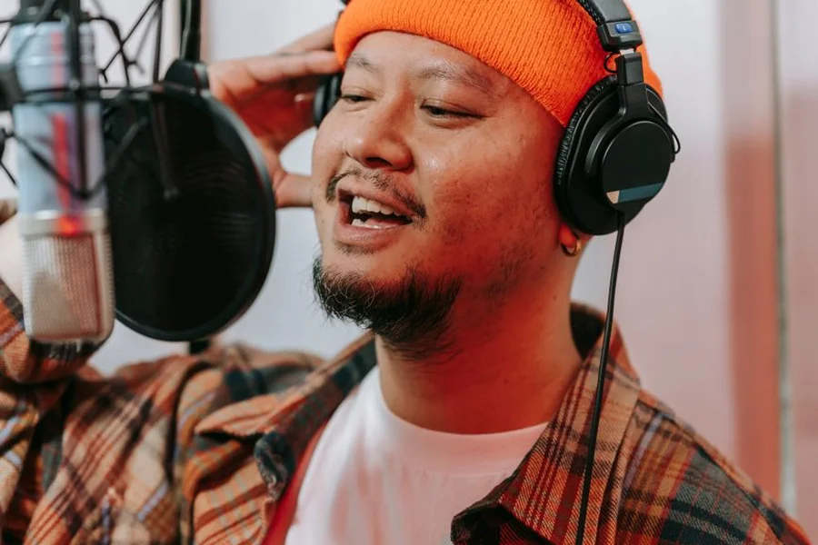 Young man singing passionately into a studio microphone during K-pop recording