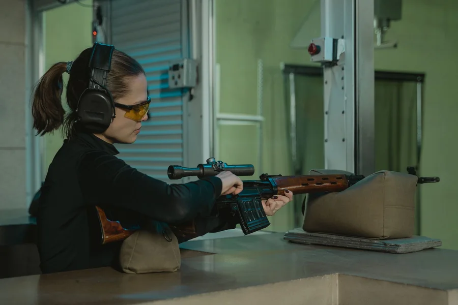 Shooter at an outdoor shooting range practicing target marksmanship with suppressed rifle
