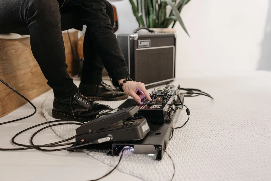 Guitar Effects Pedal Knobs Guitarist adjusting control knobs on audio effects pedal with patch cables